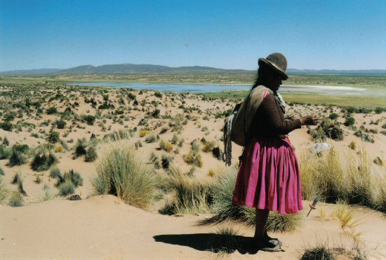 woman spinning wool with the canal in the background